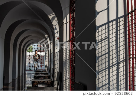 At evering the light though perforated sheet steel. Sun shinning down at a woman against the wall. 92538602