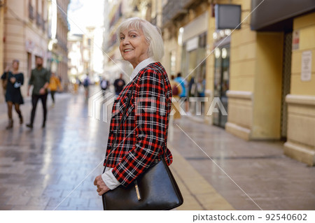 Trendy pensioner female walking outdoors in town 92540602