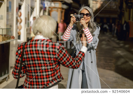 Enthusiastic lady with camera taking photos on street Enthusiastic lady with camera taking photos on street 92540604