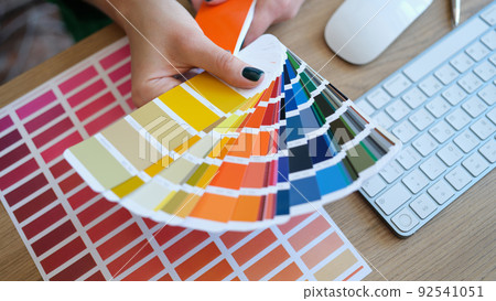 Woman designer holding fan of colourful samples in hand Woman designer holding fan of colourful samples in hand 92541051