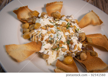 Oriental recipe aubergine and chickpea fatteh, pita, Greek yogurt, roasted pine nuts, zaatar Oriental recipe aubergine and chickpea fatteh, pita, Greek yogurt, roasted pine nuts, zaatar 92541560