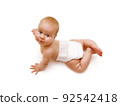 A tanned Caucasian baby in a white diaper crawls on his hands and looks up. View from above. Isolated on a white background 92542418
