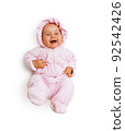 a pretty laughing girl in a pink jumpsuit is lying on her back and kicking her legs. View from above. Isolated on white 92542426