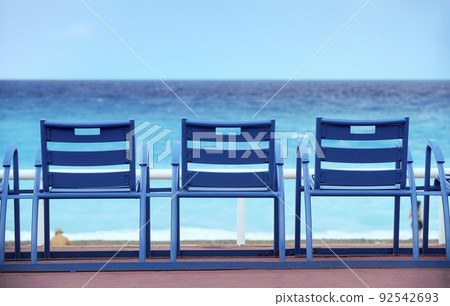 Blue armchairs on the "promenade des Anglais" in Nice on the french riviera in front of the mediterranean sea 92542693