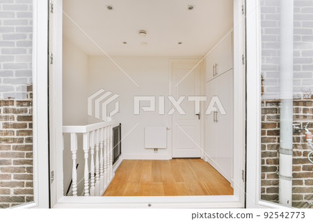 Closed white door of room located near framed pictures and stylish lamp on top of stairway at home Closed white door of room located near framed pictures and stylish lamp on top of stairway at home 92542773