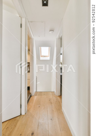 Retro cabinet with decorations and mirror located near stairway and door into living room in corridor of house 92542812