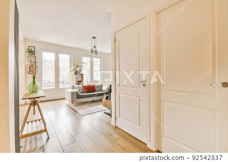 Interior of stylish living room with comfortable sofa and armchairs with cushions placed on carpet around table in modern apartment 92542837