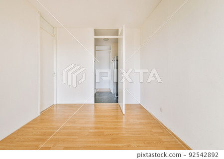 Interior of empty modern apartment with geometric design with entrance door and white walls and parquet floor illuminated with lamp 92542892