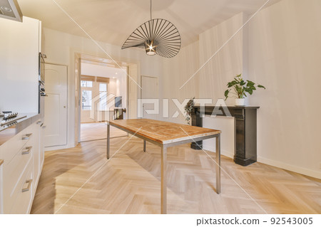 Interior of light kitchen and dining room with balcony doors in contemporary apartment at daytime Interior of light kitchen and dining room with balcony doors in contemporary apartment at daytime 92543005