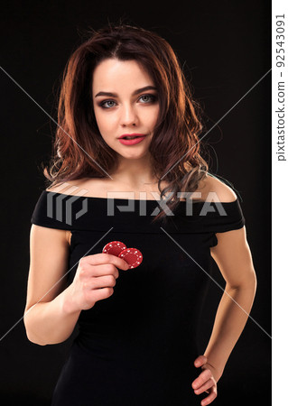 Smiling girl holding a gambling chips in her hands on black background. 92543091