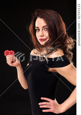 Smiling girl holding a gambling chips in her hands on black background. 92543113