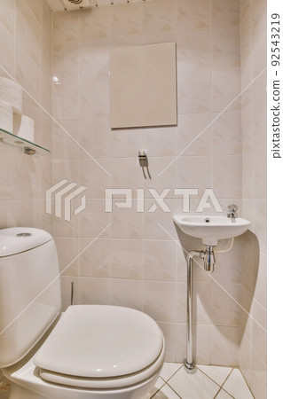 Flush toilet located between sink and shower in small tiled bathroom of contemporary apartment Flush toilet located between sink and shower in small tiled bathroom of contemporary apartment 92543219