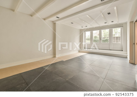 Interior of empty modern apartment with geometric design with entrance door and white walls and tiled floor illuminated with lamp 92543375