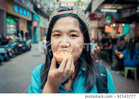 Women with egg tart famous local sweet in Macau Women with egg tart famous local sweet in Macau 92543777