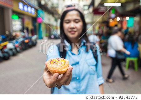Women with egg tart famous local sweet in Macau 92543778