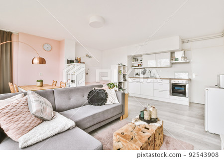 Table with chairs and flowers located near lounge area and kitchen in spacious room of contemporary apartment Table with chairs and flowers located near lounge area and kitchen in spacious room of contemporary apartment 92543908
