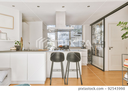 Home interior design of modern loft apartment with open kitchen in minimalist style and spacious dining zone with table and chairs 92543998