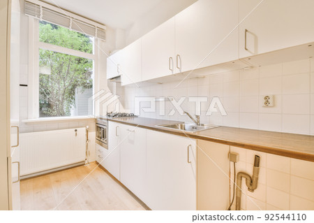 Corner cupboards and table with chairs located in light kitchen of contemporary flat Corner cupboards and table with chairs located in light kitchen of contemporary flat 92544110