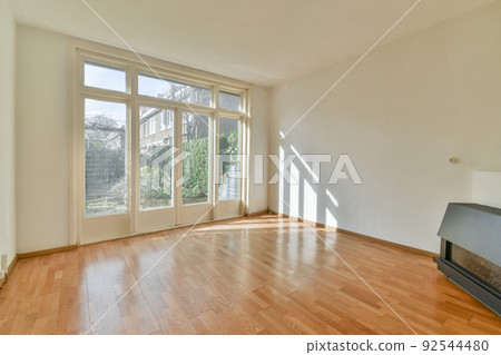 Modern counters with stools placed on wooden floor near electric fireplace in spacious room with white walls 92544480