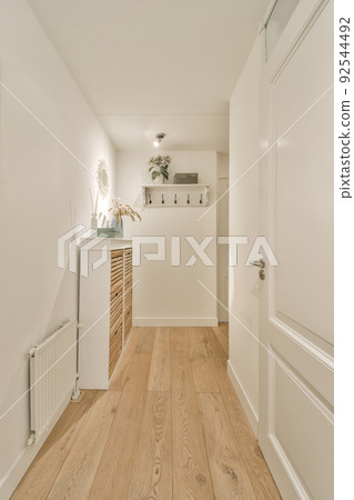 Light narrow hallway with many doors in white walls and glowing lamp over lumber floor 92544492