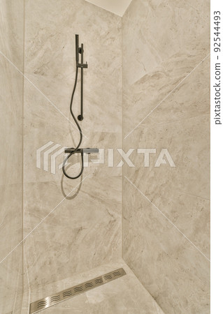Shower faucets attached to tiled wall near glass partition and ornamental curtail in washroom at home 92544493