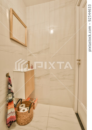 Interior of narrow restroom with sink and wall hung toilet with white walls and checkered floor 92544633