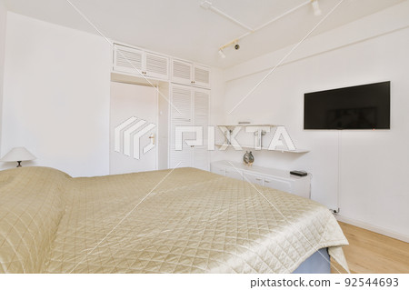 Home interior design of bedroom with bed,tv and wooden wardrobe placed in corner near window in modern apartment Home interior design of bedroom with bed,tv and wooden wardrobe placed in corner near window in modern apartment 92544693