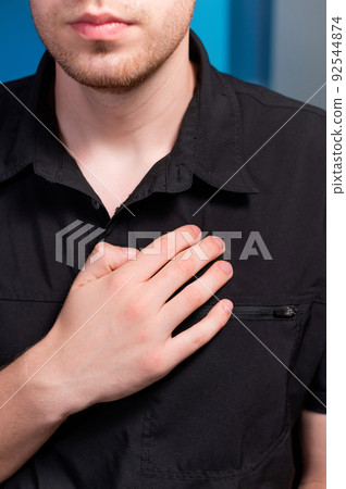 A young man stands and makes himself a lymphatic massage with his hand in the chest area, close-up A young man stands and makes himself a lymphatic massage with his hand in the chest area, close-up 92544874