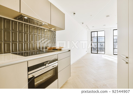 Interior of empty white kitchen with windows and wooden parquet floor Interior of empty white kitchen with windows and wooden parquet floor 92544907