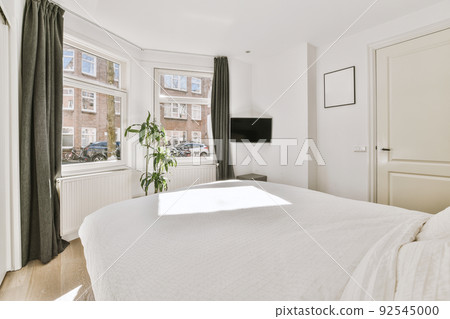 Home interior design of bedroom with bed and wooden wardrobe placed in corner near window in modern apartment 92545000