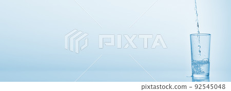 Pouring water into glass on blue background. Water spilled on the table. Pouring water into glass on blue background. Water spilled on the table. 92545048