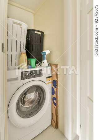 Modern flush toilet and ceramic sink installed on white tiled walls near mirror and towel in small restroom at home Modern flush toilet and ceramic sink installed on white tiled walls near mirror and towel in small restroom at home 92545075