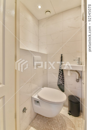 Glass partition between shower tap and wall hung toilet in modern restroom at home 92545078