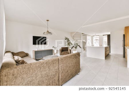 Contemporary open plan kitchen with dining table set and gray sofa in light spacious room Contemporary open plan kitchen with dining table set and gray sofa in light spacious room 92545145