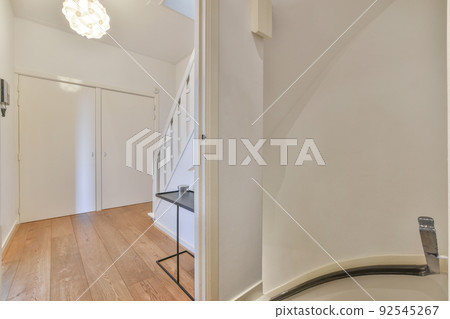 White hallway with wooden stairway leading to second floor of modern luxury apartment with minimalist interior design White hallway with wooden stairway leading to second floor of modern luxury apartment with minimalist interior design 92545267