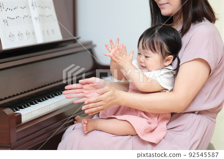 1 year old girl and mom playing upright piano 92545587