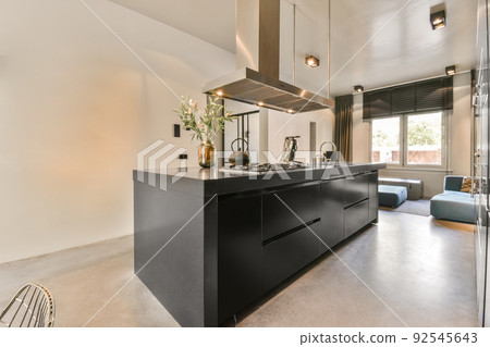 Contemporary minimalist style interior design of light studio apartment with wooden table and chairs in dining zone between open kitchen and living room with white walls and parquet floor Contemporary minimalist style interior design of light studio apartment with wooden table and chairs in dining zone between open kitchen and living room with white walls and parquet floor 92545643