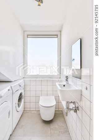 Wall hung toilet and small sink in corner in lavatory room with beige tile Wall hung toilet and small sink in corner in lavatory room with beige tile 92545785