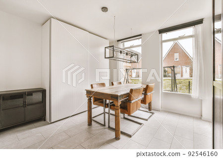 Contemporary open plan kitchen with dining table set and gray sofa in light spacious room 92546160
