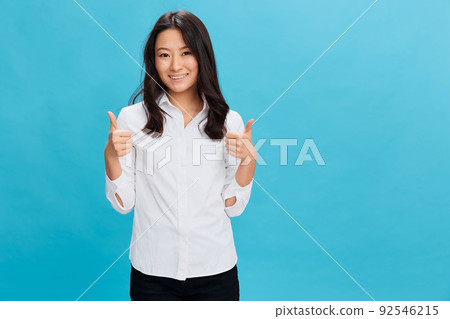 Joyful cute Asian businesswoman in classic office dress code show thumb up gesture Like posing isolated on over blue studio background. Cool business offer. People Emotions Business concept 92546215