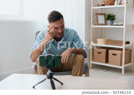 Self-confident attractive influencer blogger record online webinar lesson for subscribers with phone at home table. Copy space. Electronic IT PC accessories Gadget addiction Online education concept 92546218