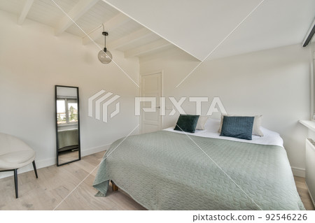 Comfortable bed placed near green wall in modern minimalist style mansard bedroom with windows 92546226