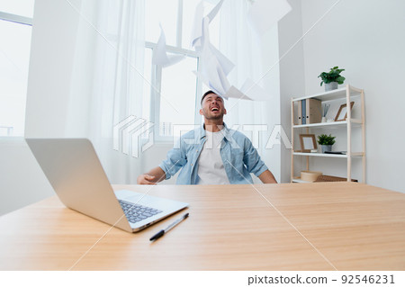 Crazy screaming irritated handsome stylish young businessman throws the paper over the table out of anger. Copy space for ad. Remote Job, Technology And Career Profession Concept 92546231