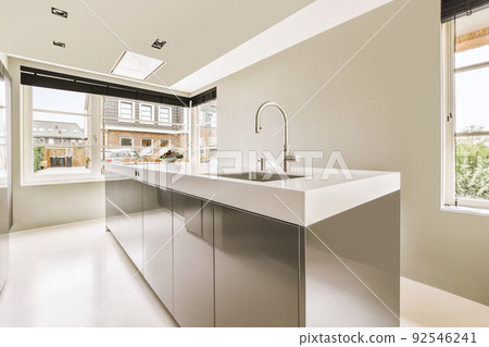 Comfortable sofa with cushions and pouf located near doors and dining area in room of contemporary apartment 92546241