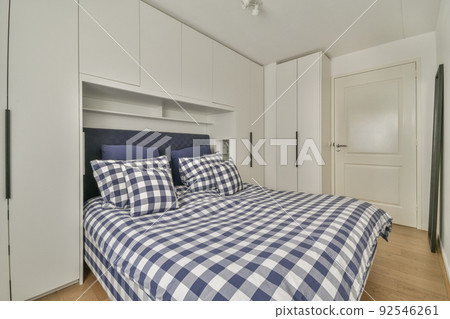 Comfortable bed with colorful pillows and warm blanket located near window in stylish bedroom with green walls Comfortable bed with colorful pillows and warm blanket located near window in stylish bedroom with green walls 92546261