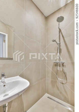 Sinks with mirrors and shower box with glass door in modern bathroom with white tiled walls Sinks with mirrors and shower box with glass door in modern bathroom with white tiled walls 92546600