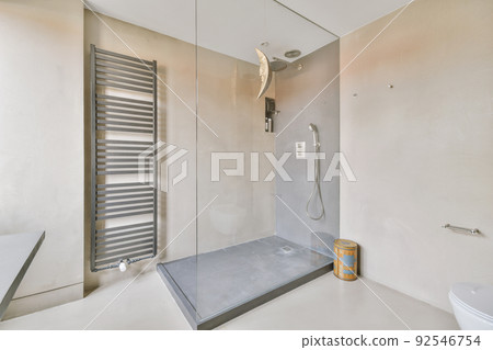 Shower faucets attached to tiled wall near glass partition and ornamental curtail in washroom at home 92546754