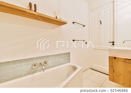 Sinks with mirrors and clean bathtub in modern bathroom with white tiled walls Sinks with mirrors and clean bathtub in modern bathroom with white tiled walls 92546866