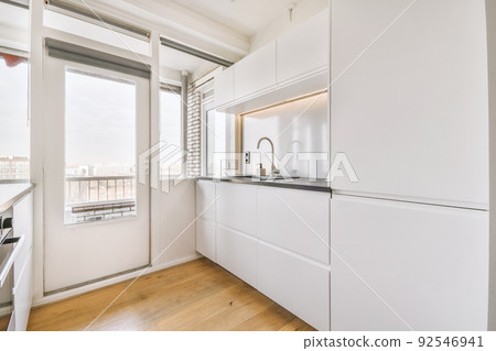 Interior of a bright kitchen with balcony doors in a modern apartment at daytime Interior of a bright kitchen with balcony doors in a modern apartment at daytime 92546941