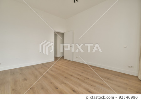 Interior of empty modern apartment with geometric design with entrance door and white walls and parquet floor illuminated with lamp 92546980